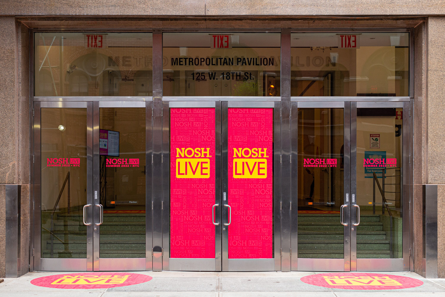 Stainless-steel doors with pink Nosh Live panels under a sign reading Metropolitan Pavilion 125 W 18th St.