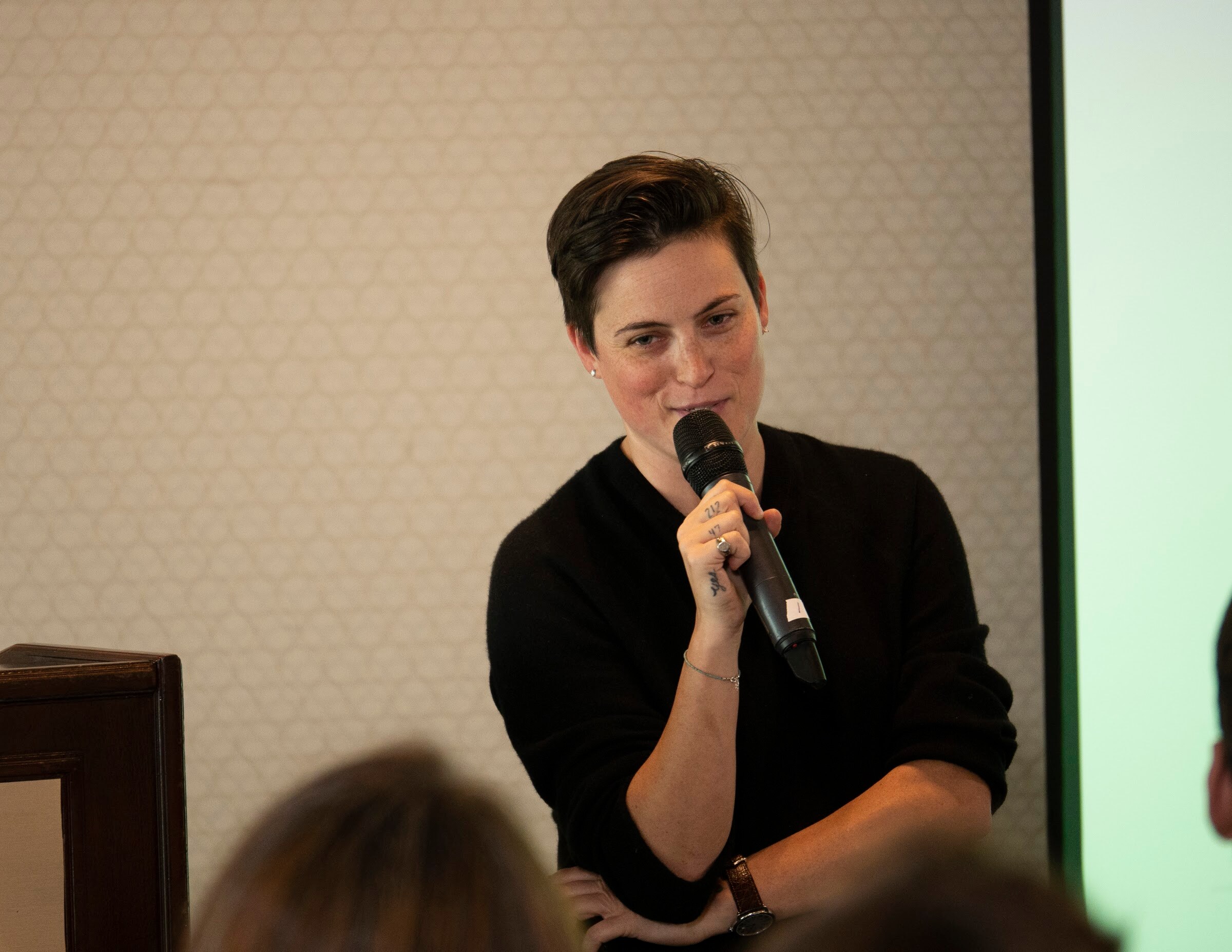 A woman in black holds a microphone and answers a question from the audience.