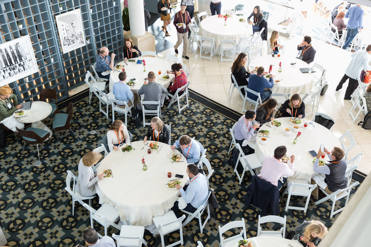 An overhead view of attendees eating lunch at round tables in the hotel atrium.