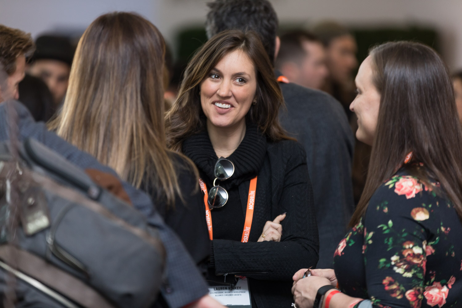 A woman in black smiles as she talks with other attendees at the networking break.