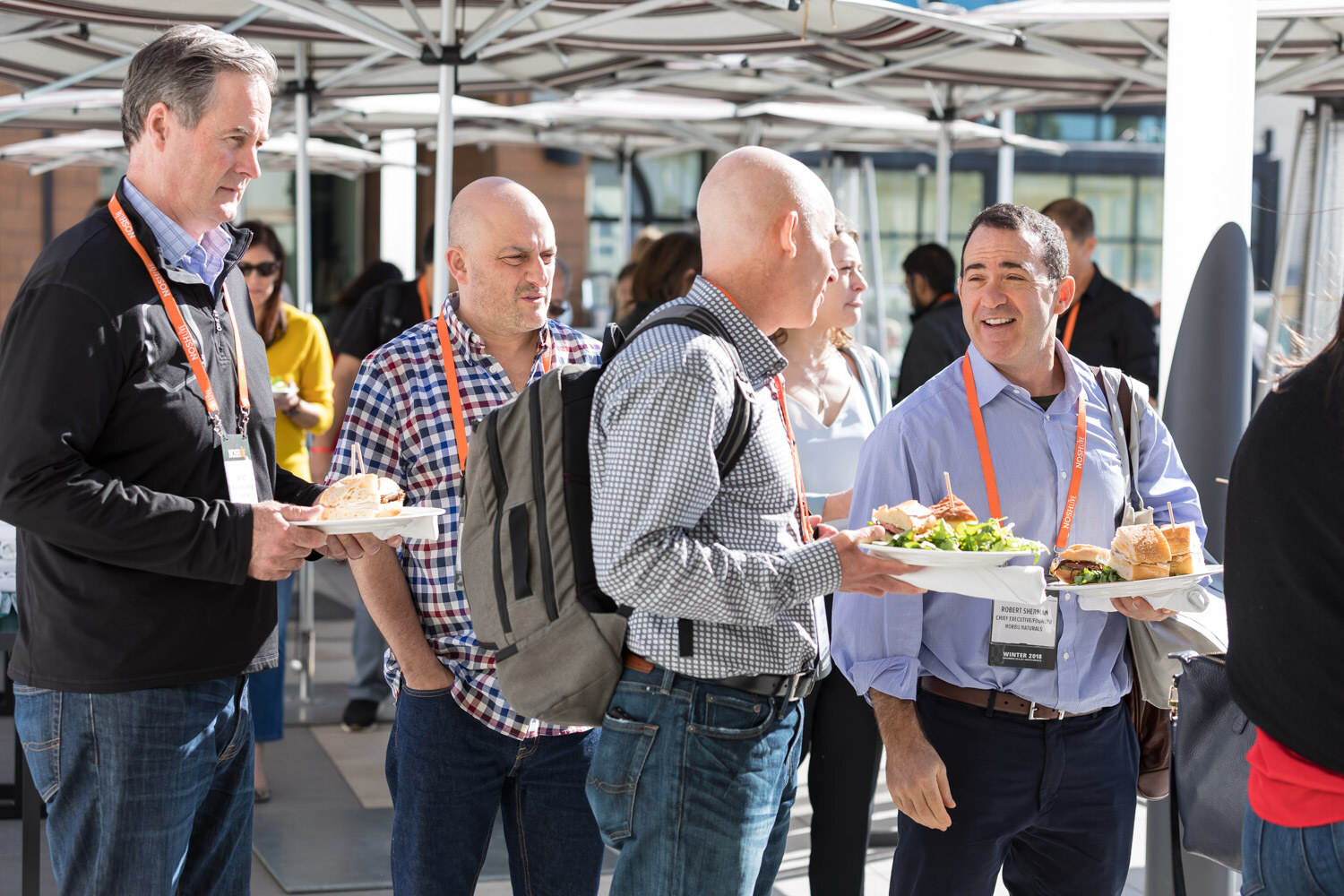 Attendees with plates of food talk during lunch on the hotel terrace.