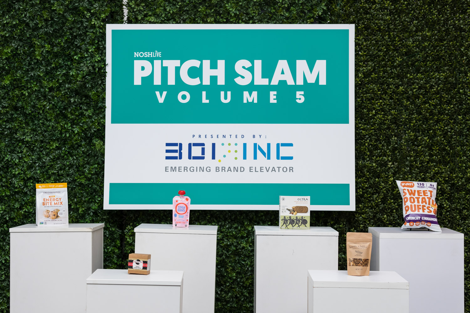 The Pitch Slam Volume 5 sign presented by Boi Inc with five products on white pedestals.