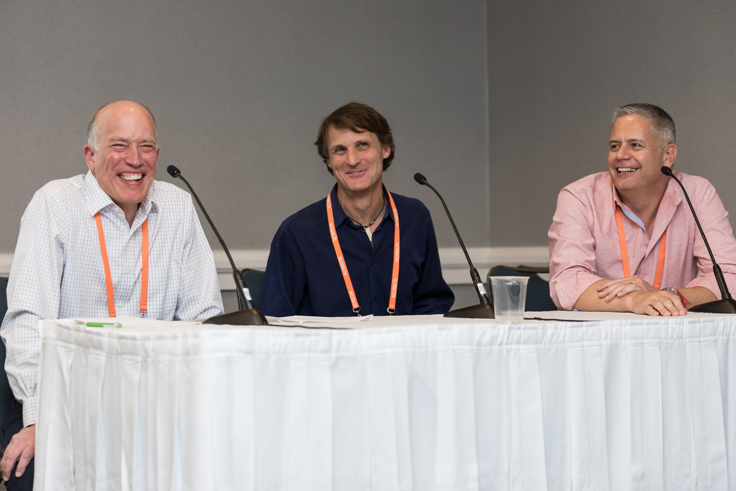 Three panelists smile and laugh at the head table during Breakout Session 1.