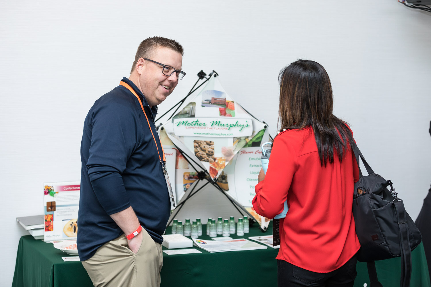 A man and a woman talk at a Mother Murphy's flavor table.
