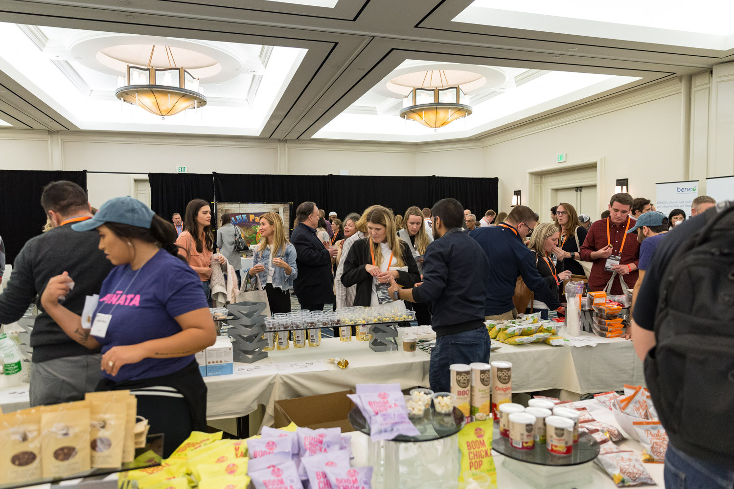 A busy ballroom expo floor with sampling tables and a staffer in a Piñata shirt.