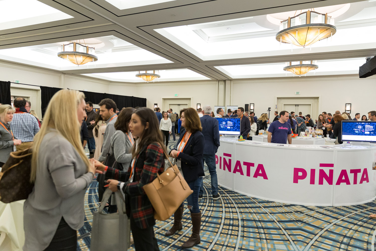 Attendees crowd the Sampling Experience and Expo past a white Piñata table.