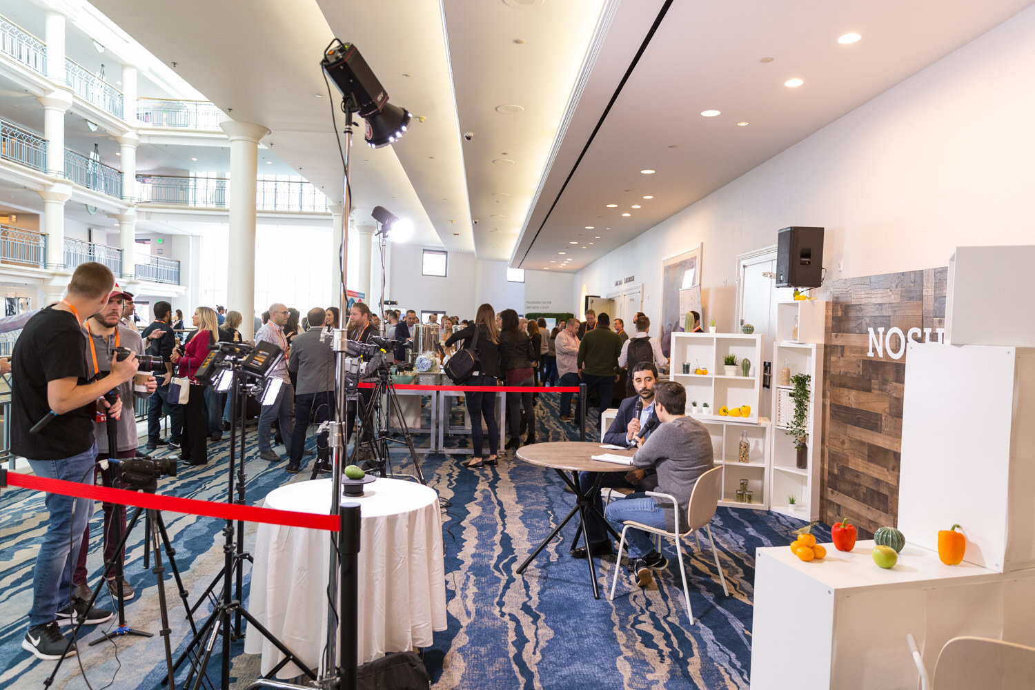 The livestream studio set beside the networking area, with a round table and Nosh Live backdrop.