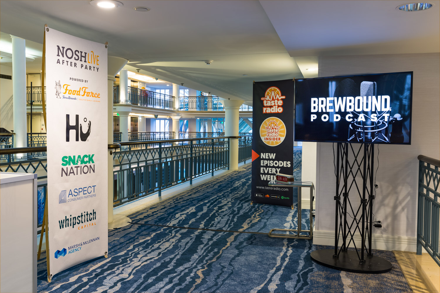 A sponsor banner and a Brewbound Podcast screen beside the second-floor railing at the hotel.