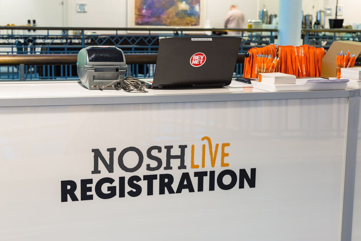 The Nosh Live Registration desk with a laptop and orange lanyards.