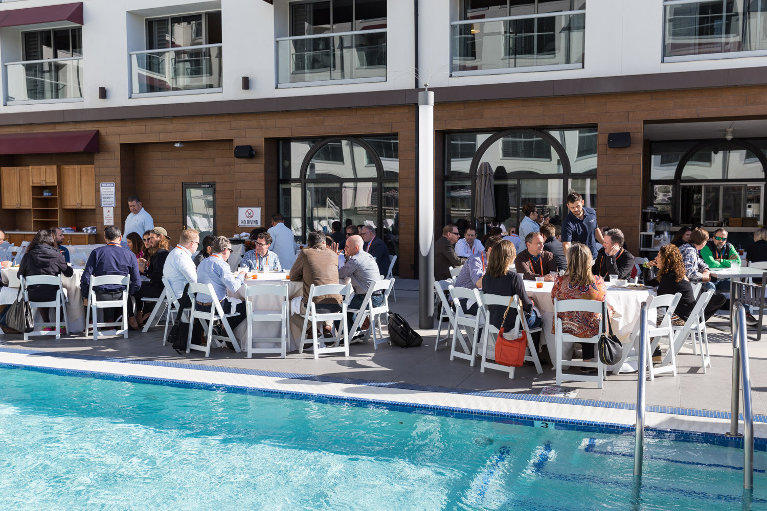 Attendees eat lunch at tables beside the rooftop pool.