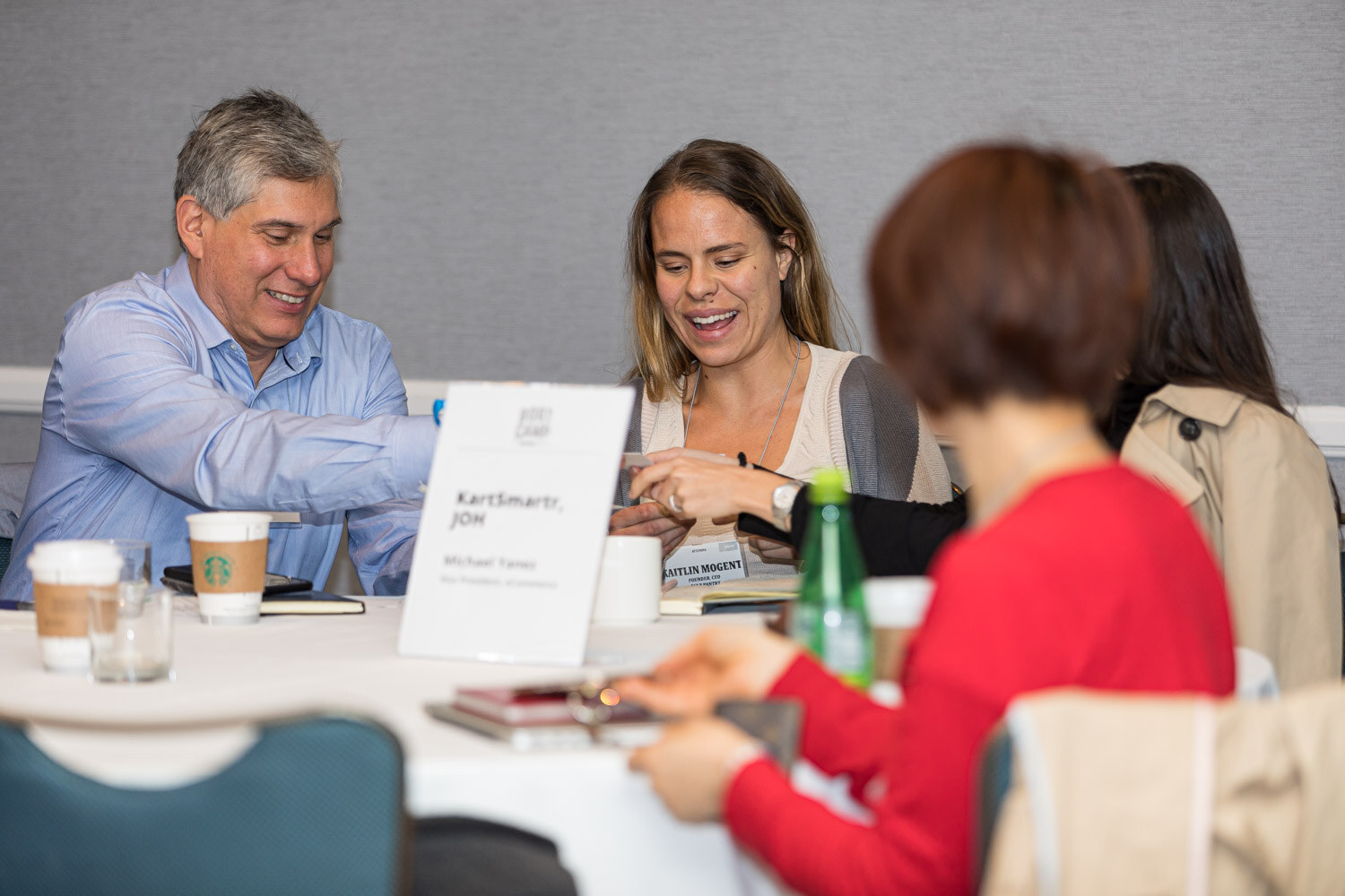Two people talking at a round table with a name card reading KartSmartr, JOH