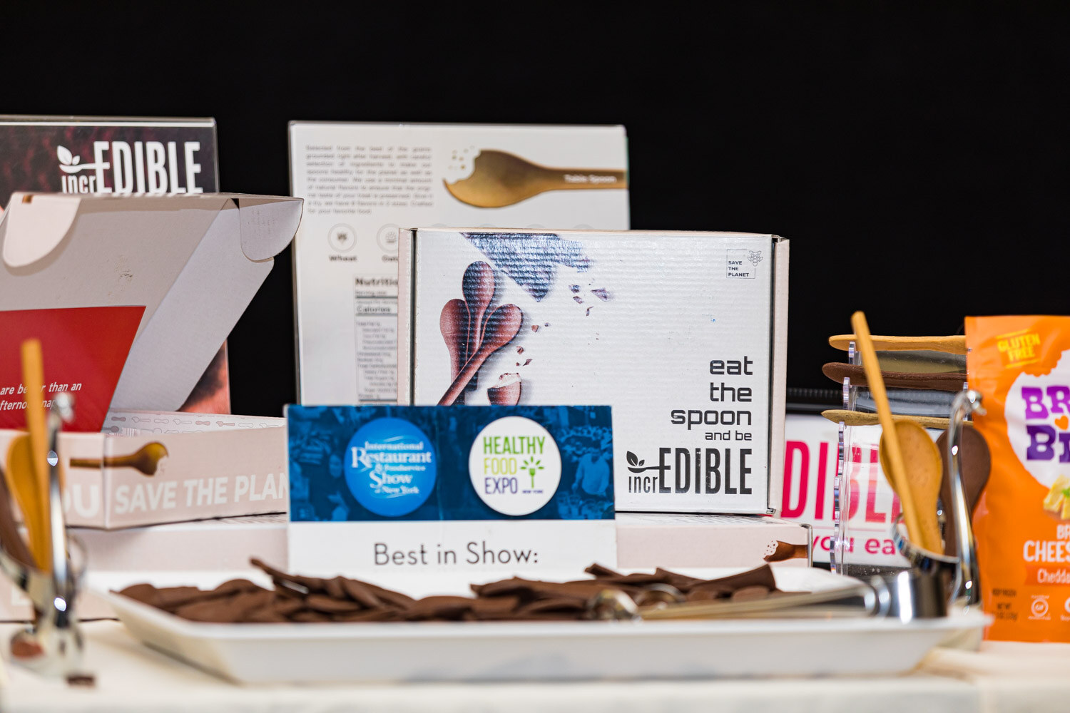 Boxes of Edible products behind a Best in Show sign and a tray of chocolate spoon samples