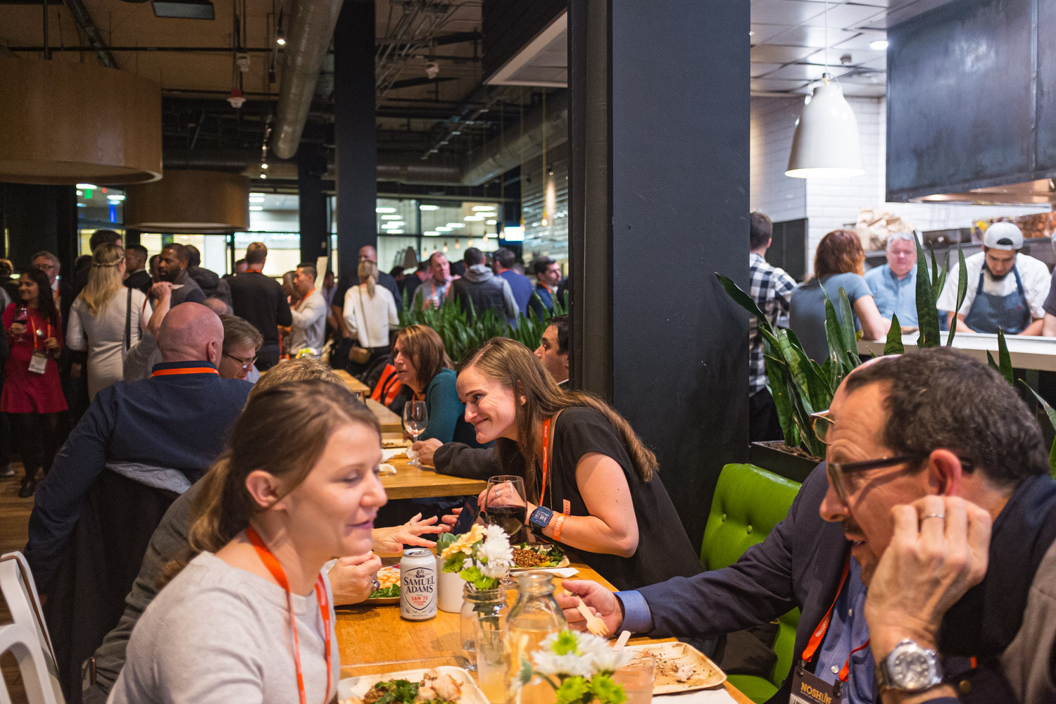 Attendees seated at a long table sharing food in a busy restaurant