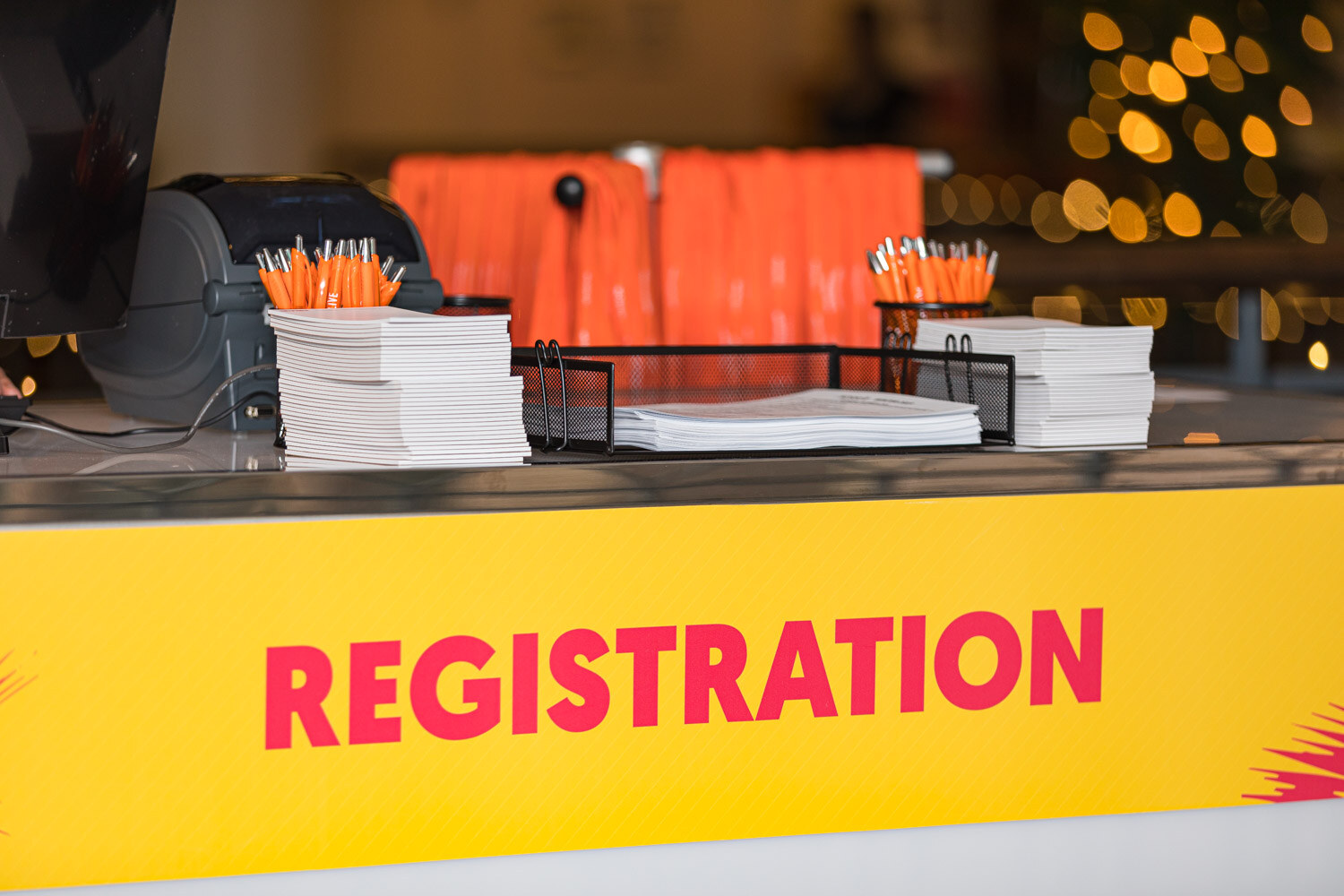 A yellow Registration sign in front of stacks of printed materials and orange lanyards