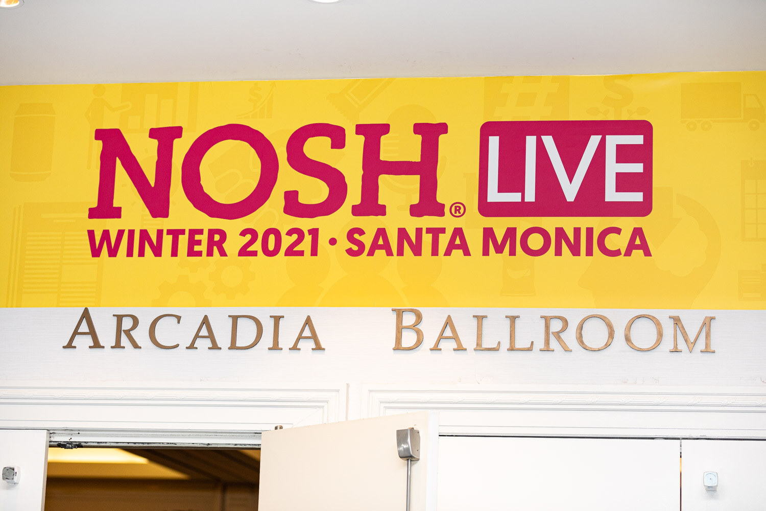 Yellow banner reading Nosh Live Winter 2021 Santa Monica above gold letters spelling Arcadia Ballroom over a partly open door.