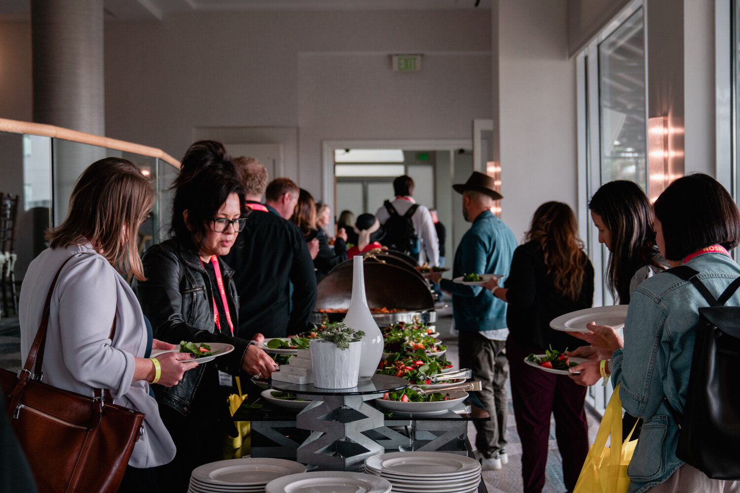 Several attendees holding plates at a buffet with salads and a covered serving dish.