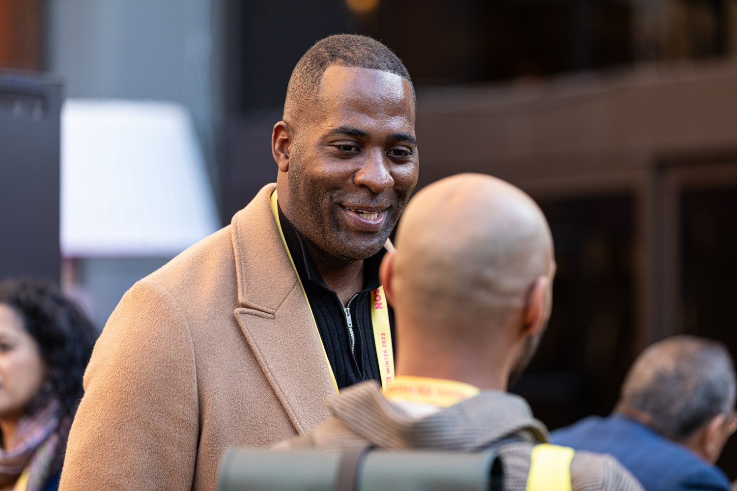 A smiling man wearing a lanyard in a crowd of attendees.