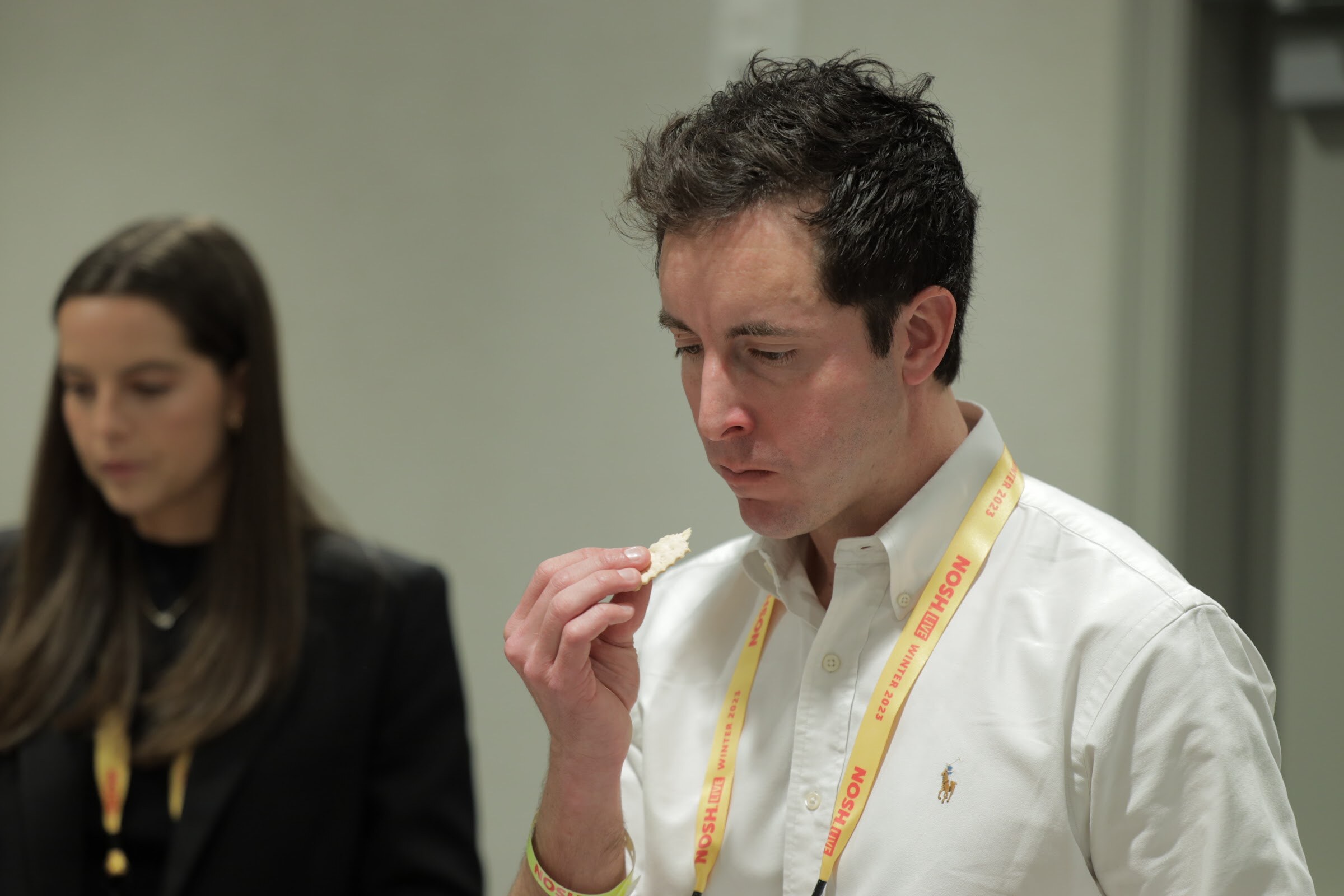 A man in a white shirt eating a cracker while a woman sits beside him.