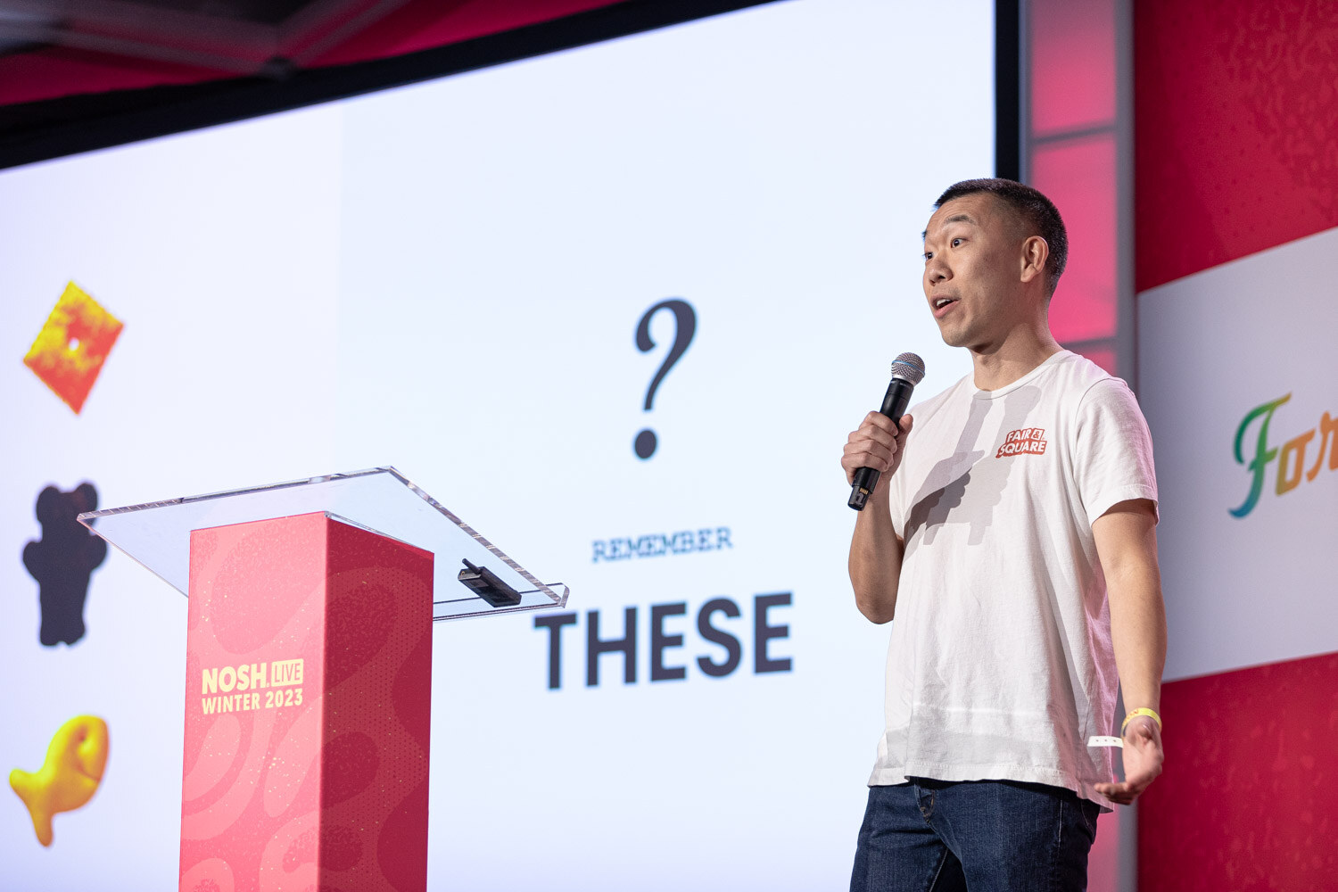 A man in a white Fair & Square t-shirt holding a microphone in front of a slide reading Remember These.