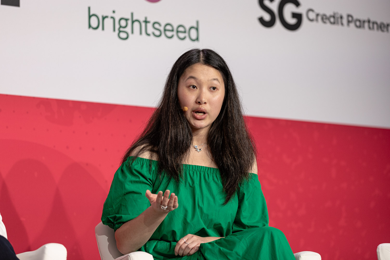 A woman in a green dress speaking on stage.