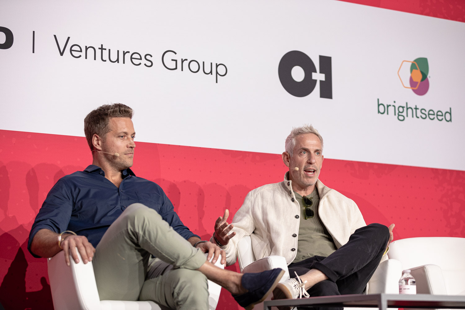 Two men seated on white chairs in front of Pepsico Ventures Group and brightseed signs.