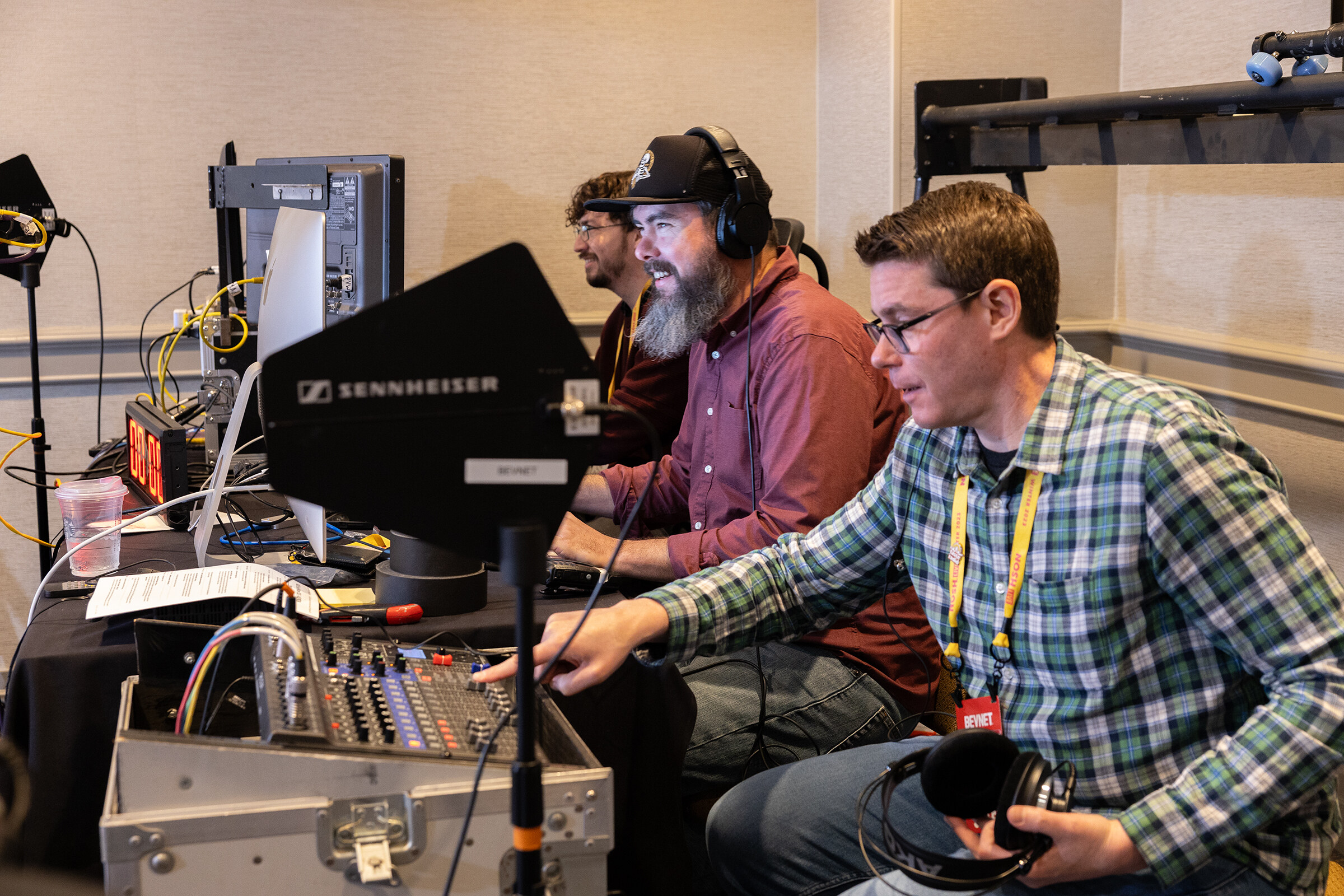 Two men at an audio mixer and monitors, one wearing headphones.