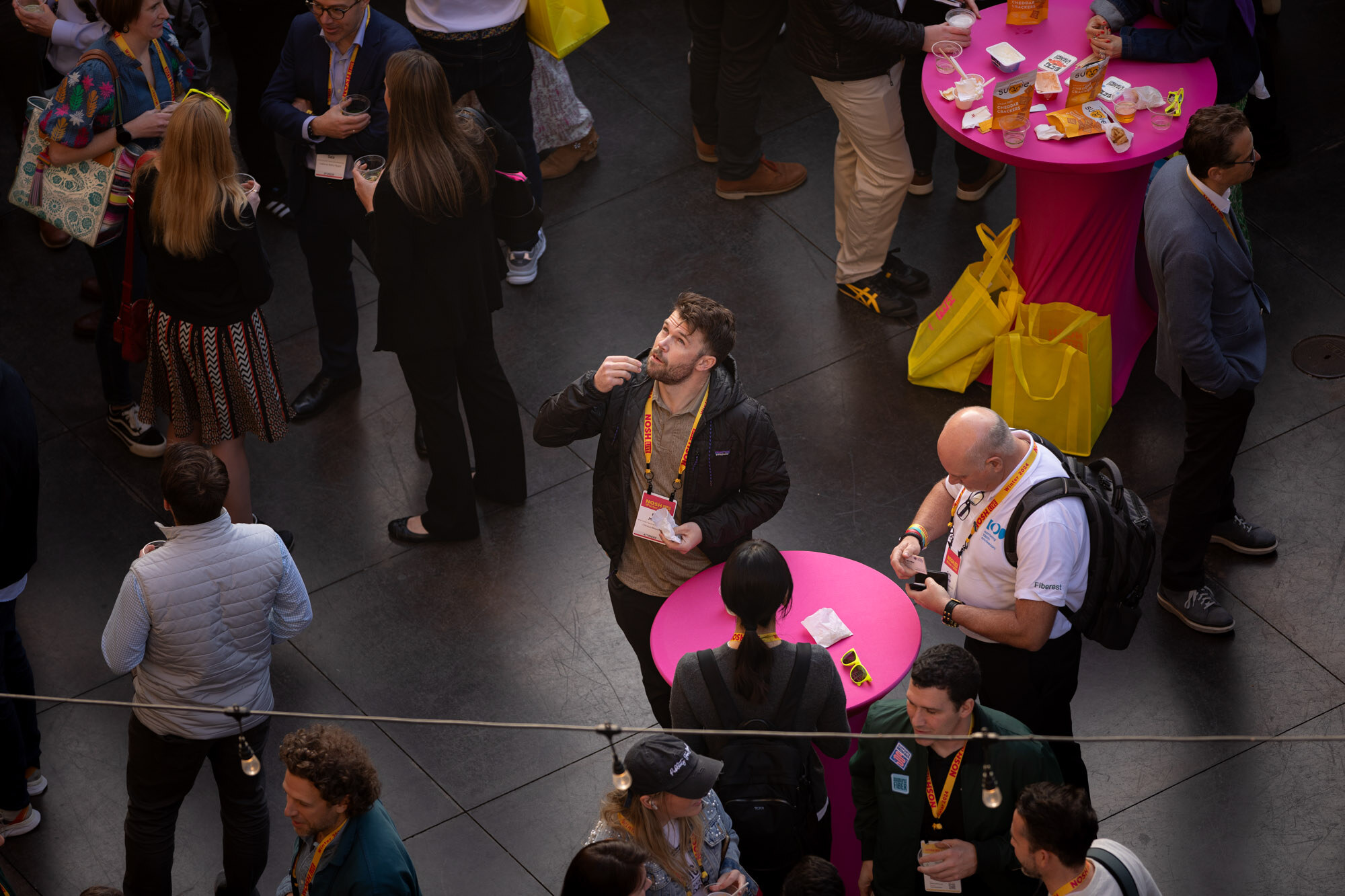 Overhead view of groups of people standing around pink round cocktail tables.