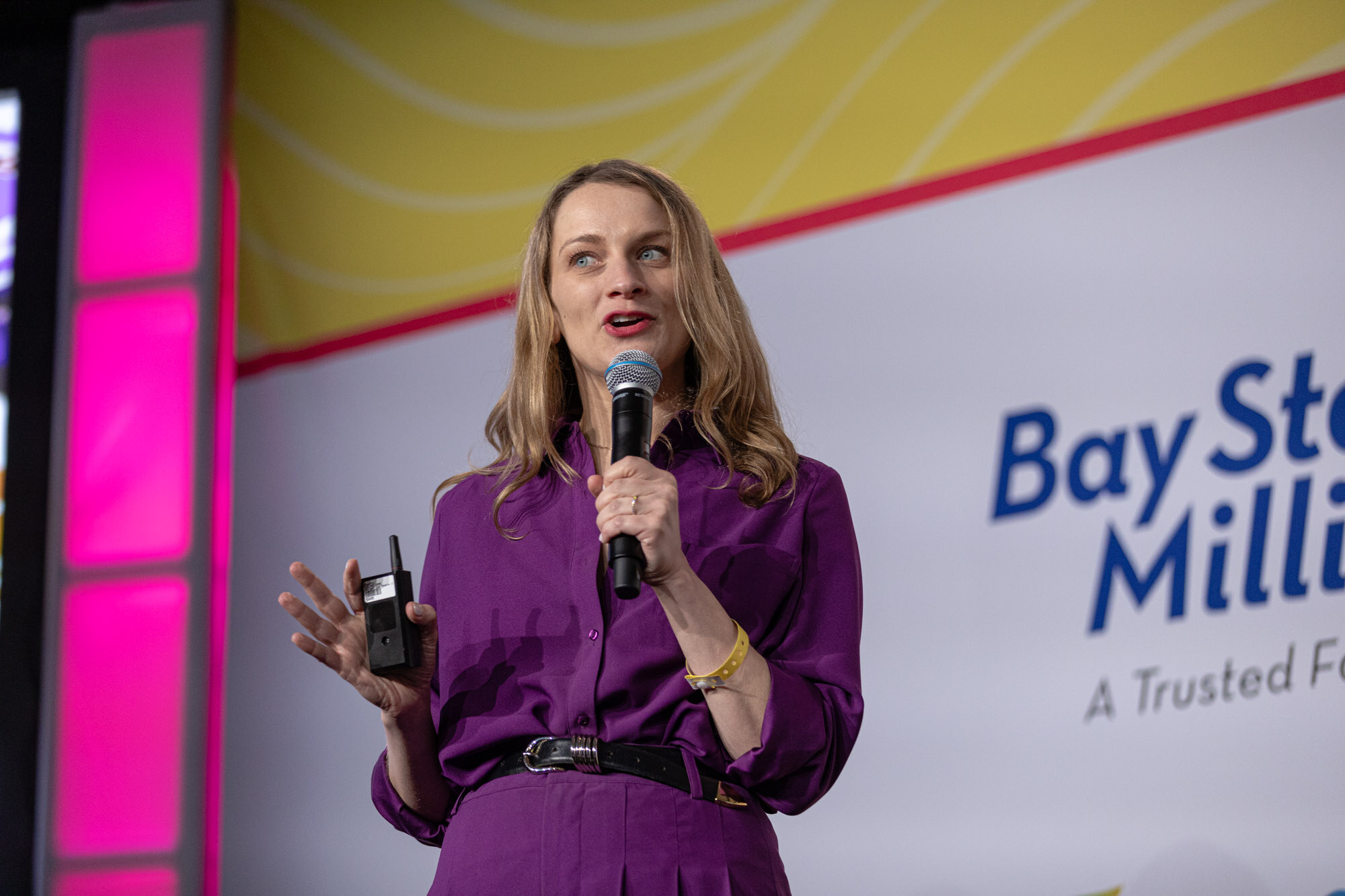 A blond woman in a purple outfit speaking in front of a slide about a viral date caramel bar.