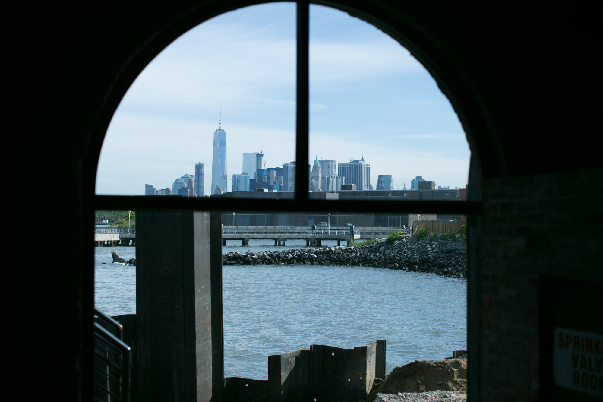 View of the Lower Manhattan skyline and the harbor through an arched window.