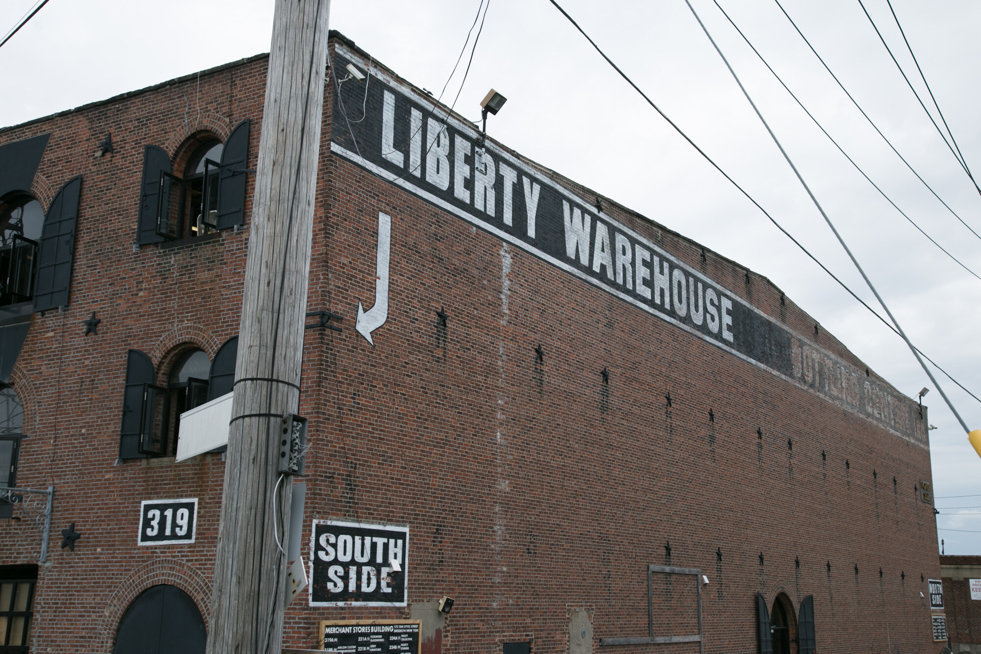 Red brick building with Liberty Warehouse painted across the top of the wall, a South Side sign and the number 319.