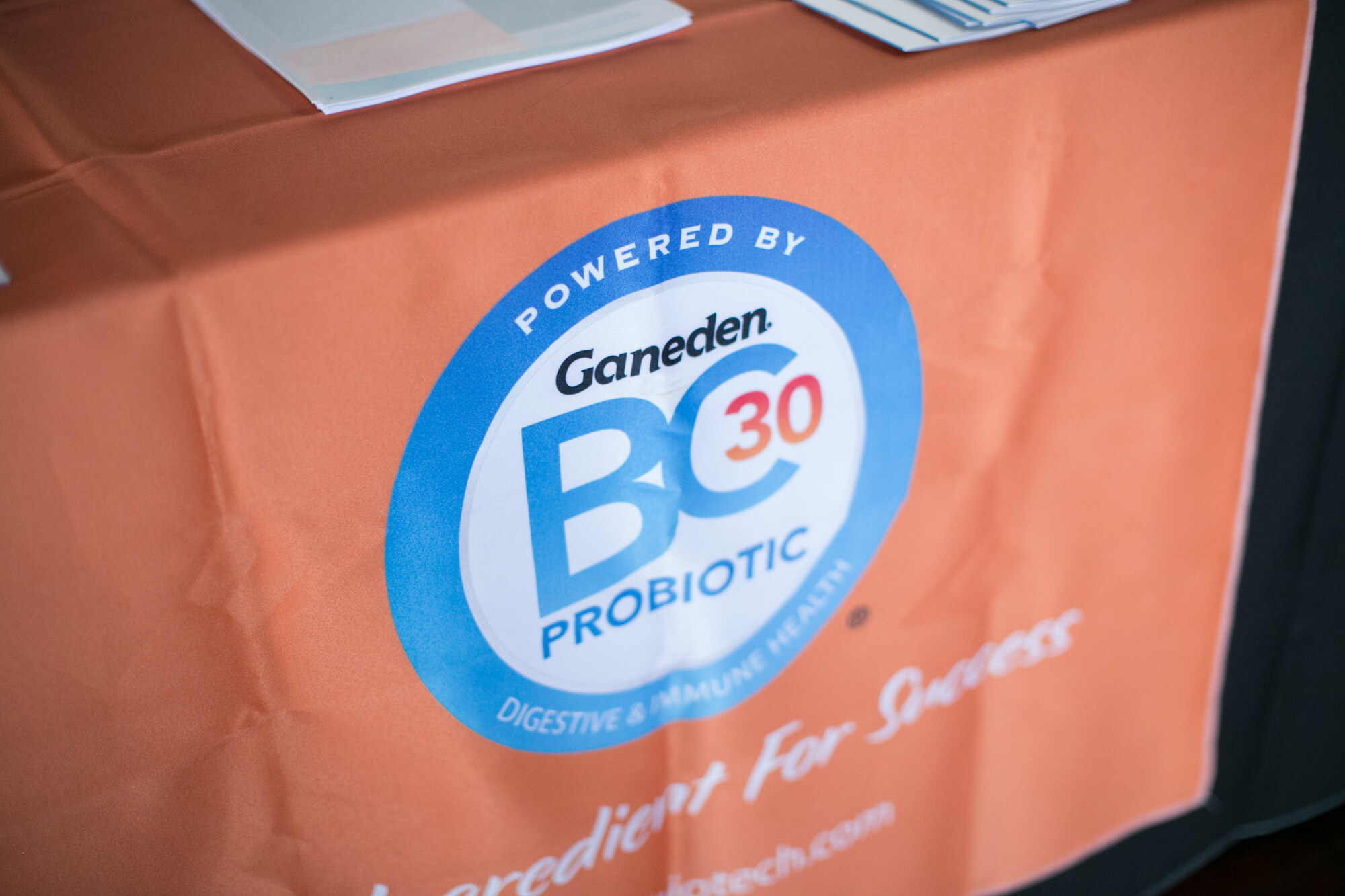 Close view of an orange table cover printed with a Powered by Ganeden BC30 Probiotic badge.
