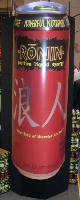 A giant red Ronin can display with Japanese characters and the tagline positive liquid synergy, with stacked cases of product at the lower edges.