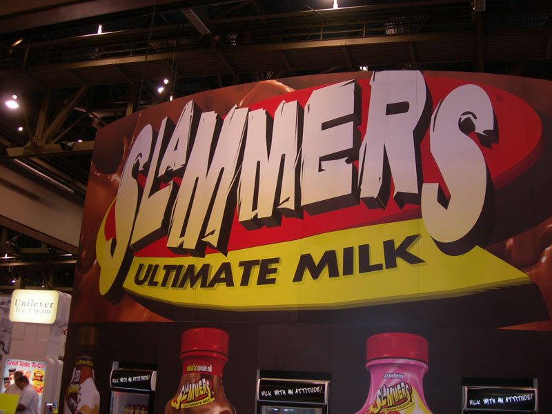 A large Slammers Ultimate Milk sign hangs above bottles of chocolate and strawberry Slammers. A Unilever Ice Cream sign appears at the lower left.