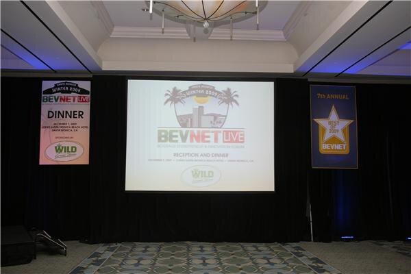 A ballroom stage with a projection screen reading BevNET Live reception and dinner, flanked by banners for the dinner sponsored by Wild and the 7th annual Best of 2009.