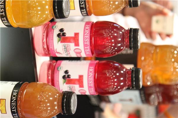 A sideways close-up of Honest Tea bottles, including red-tinted bottles with pink labels and amber bottles with black caps.