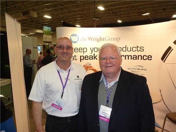 Two men with exhibitor badges and lanyards stand together in front of a The Wright Group backdrop that also shows the Superblend logo.