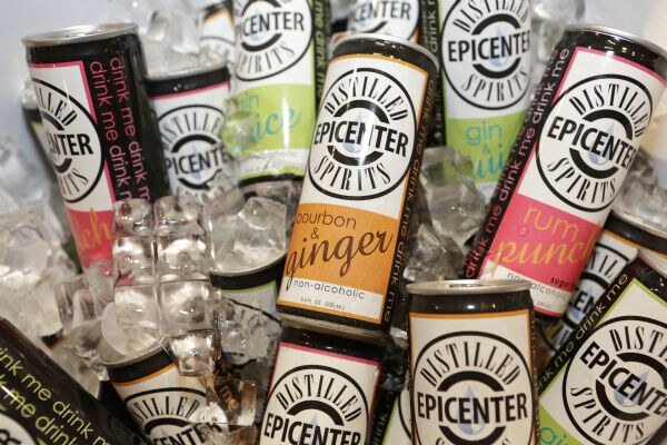 Cans of Distilled Epicenter Spirits non-alcoholic drinks, including bourbon & ginger and rum punch, packed in ice. Labels read "drink me drink me."