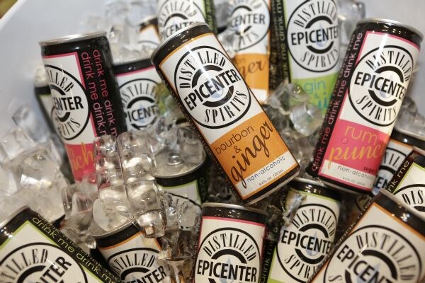 Cans of Distilled Epicenter Spirits non-alcoholic drinks, including bourbon & ginger and rum punch, lying in a bed of ice cubes.