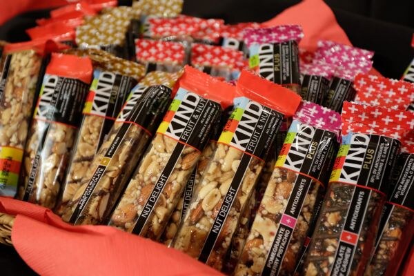 A close view of KIND bars, including Nut Delight and Pomegranate Blueberry Pistachio varieties, arranged in a basket lined with red fabric.