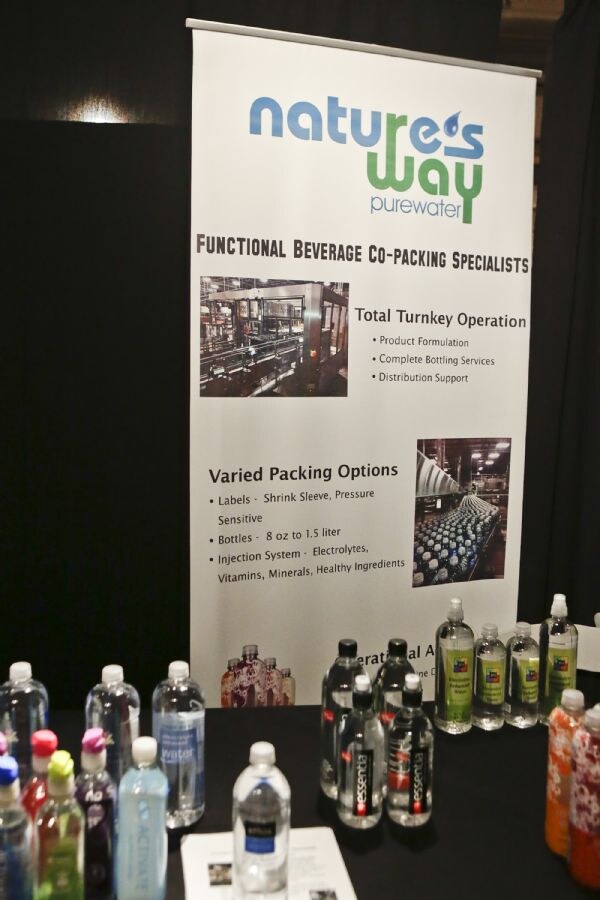 A Nature's Way Purewater banner reading Functional Beverage Co-packing Specialists above a table of bottled waters, including Essentia, in a range of colors.