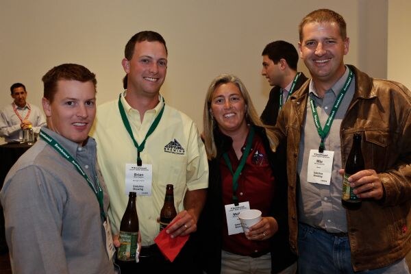 Four smiling attendees wearing green Brewbound lanyards pose together, some holding beer bottles. Brian, second from left, wears a light yellow shirt with an Eddyline Brewing logo.