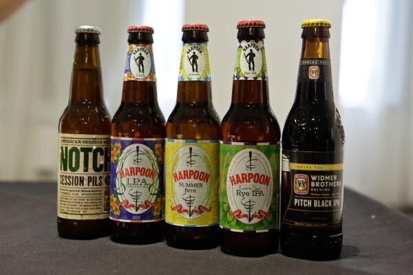 Five bottled beers stand in a row on a table: Notch Session Pils, Harpoon IPA, Harpoon Summer Beer, Harpoon Rye IPA and Widmer Brothers Brewing Pitch Black IPA.