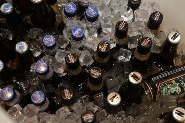 Bottles of Samuel Adams and other beers sit in a tub of ice, with a can lying among them.