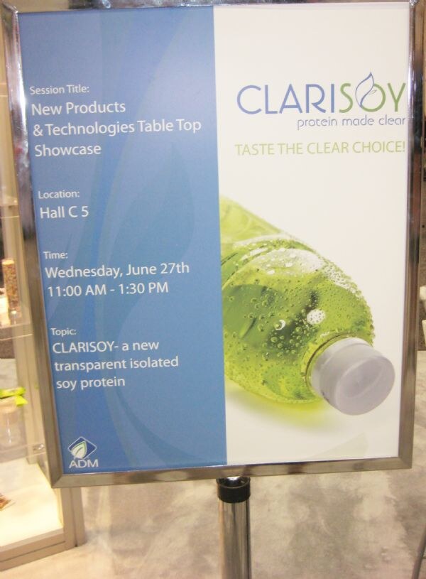 A framed sign for Clarisoy, protein made clear, with a green bottle. It announces a New Products & Technologies Table Top Showcase in Hall C 5 on Wednesday, June 27, with an ADM logo.