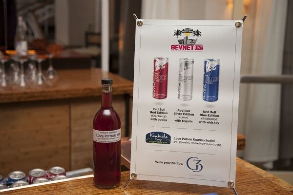 A bottle of Love Potion Kombucha stands beside a BevNET Live sign listing Red Bull cocktails, a Kombucha Kamp Love Potion Kombuchatini by Hannah's Homebrew Kombucha, and wine by G3.