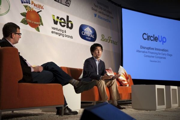 Two men sit on orange chairs on stage; one gestures while speaking. A screen reads CircleUp, Disruptive Innovation: Alternative Financing for Early-Stage Consumer Companies.