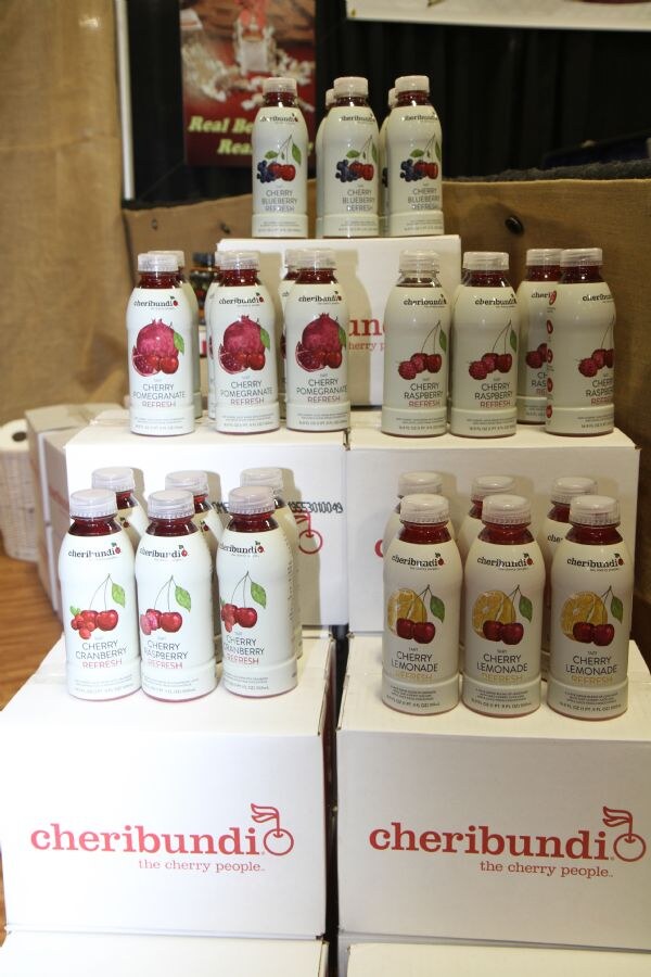 Bottles of Cheribundi cherry juice drinks are stacked on Cheribundi boxes, in flavors including cherry blueberry, pomegranate, raspberry, cranberry raspberry and cherry lemonade.