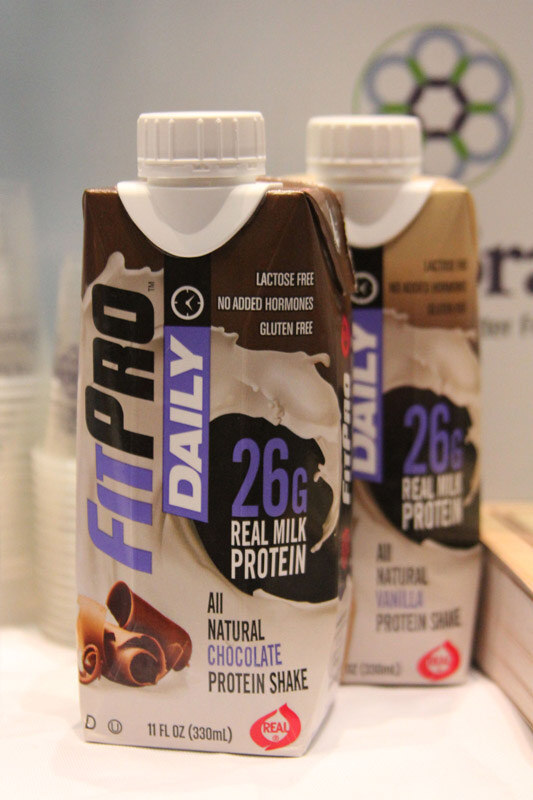 Two cartons of FitPro Daily protein shake, chocolate in front and vanilla behind, each labeled 26g real milk protein, on a white surface.