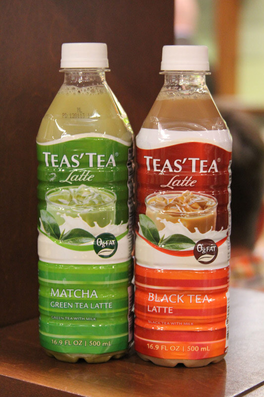 Two 16.9 fl oz bottles of Teas' Tea Latte stand side by side: Matcha Green Tea Latte with a green label and Black Tea Latte with a red and orange label.