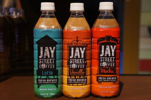 Three Jay Street Coffee bottles in a row: Latte with a teal label, Vanilla with a yellow-orange label and Mocha with a red-orange label, each marked fresh brewed.